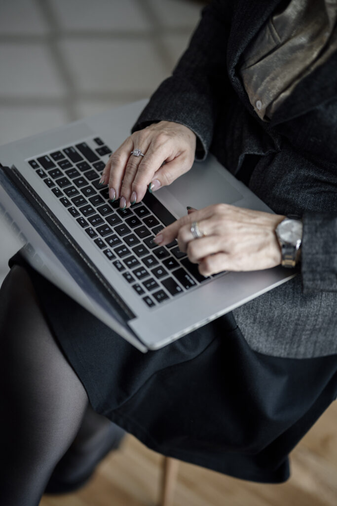Close-up of a person typing on a laptop keyboard at a desk.